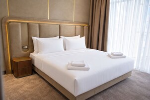 Een hotelkamer met een groot bed, een nachtkastje en een raam met gordijnen.