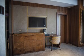A modern room with a wooden cabinet, a desk, a chair, and a television mounted on the wall. - The Arte Hotel (Yerevan)