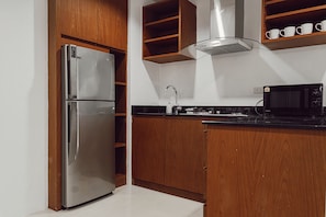 Una cocina con armarios de madera, un refrigerador de acero inoxidable, un microondas y una estufa a gas.