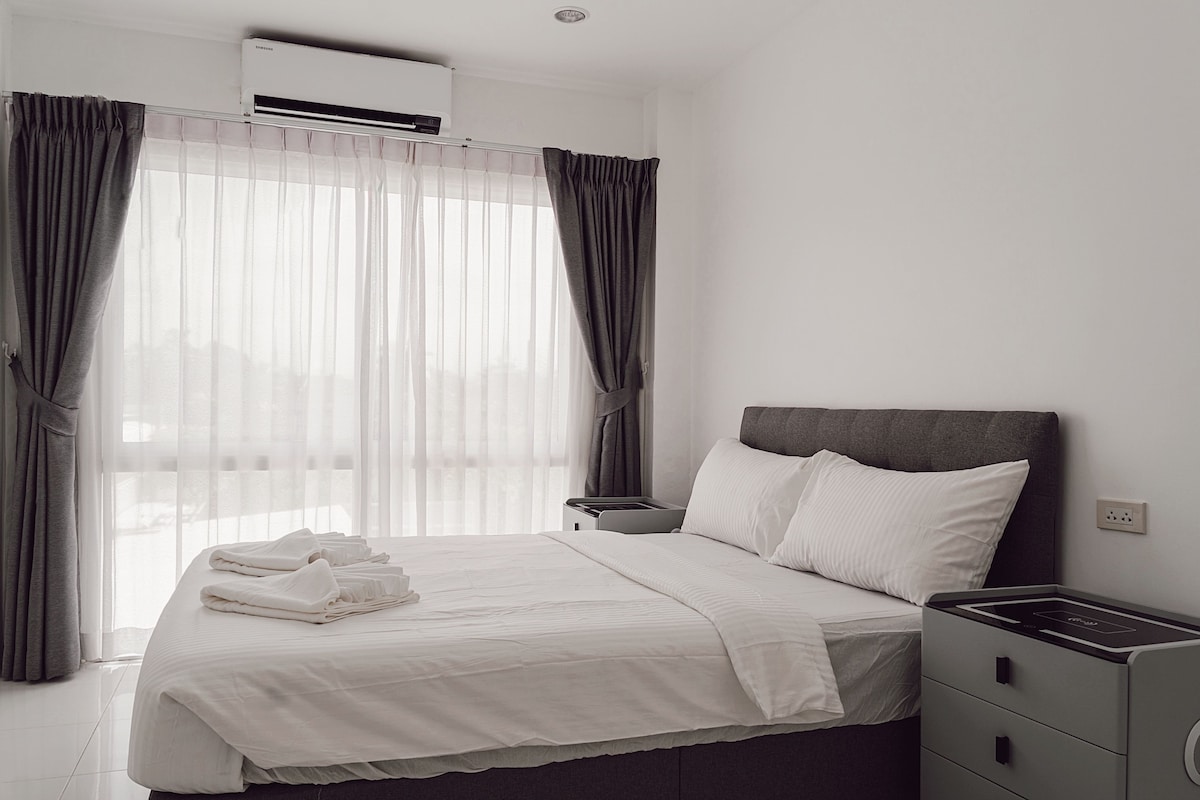 Habitación de hotel con cama, mesita de noche y unidad de aire acondicionado.