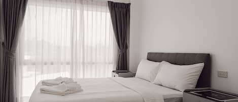 A hotel room with a bed, bedside table, and a wall-mounted air conditioner.
