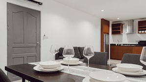 Un comedor con una mesa dispuesta para cuatro personas, incluyendo platos, tazones y copas de vino.
