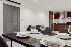 Un comedor con una mesa dispuesta para cuatro personas, incluyendo platos, tazones y copas de vino.