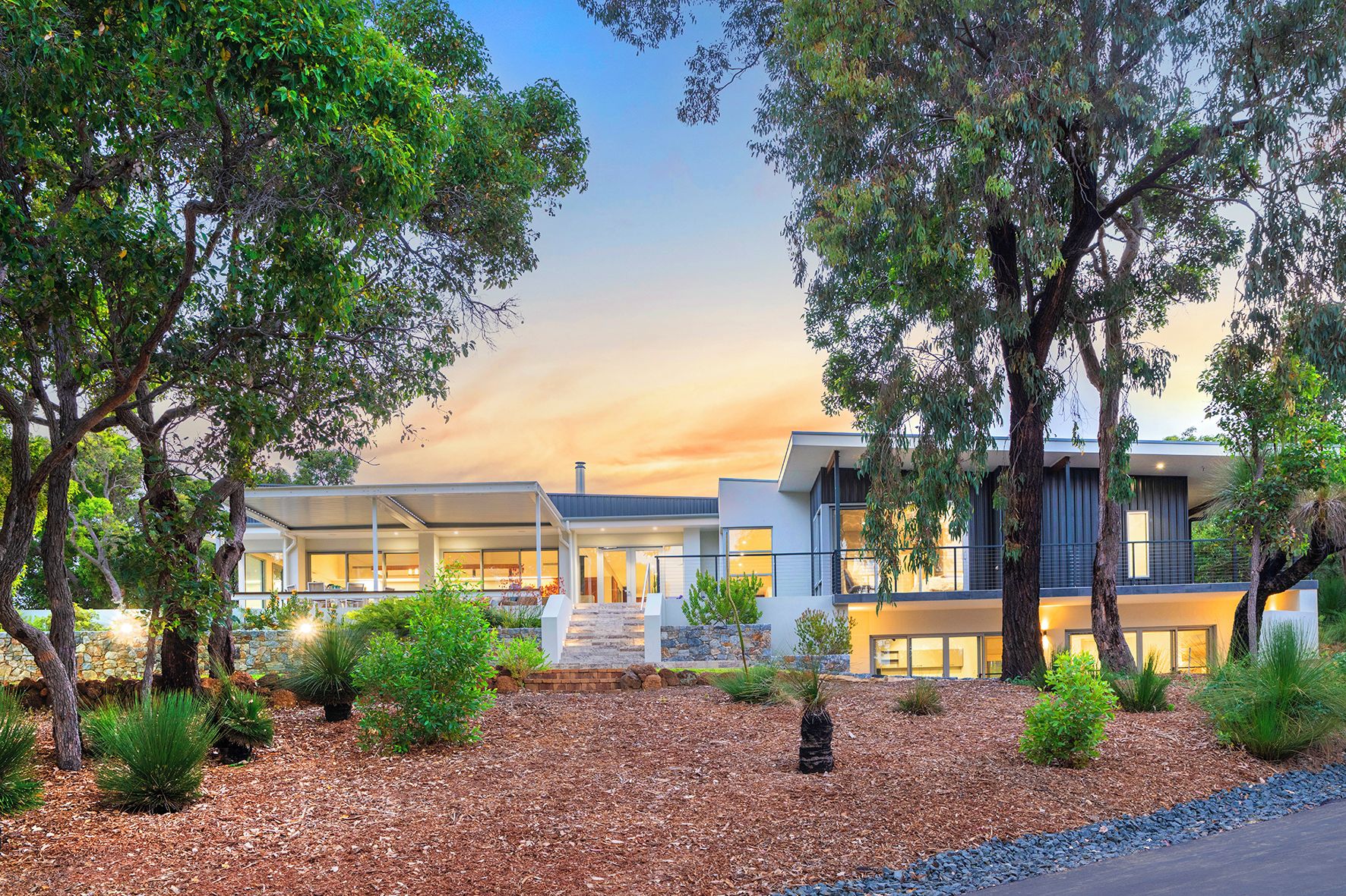 A modern building with a covered outdoor area, surrounded by trees and landscaped garden.