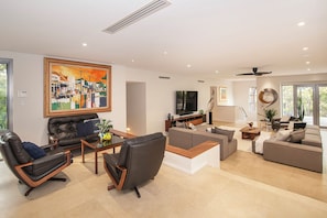 A modern living room with a large painting, a flat-screen TV, and a dining area. - Amira Vista - Views of Eagle Bay (Eagle Bay)