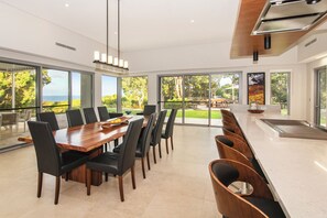A modern kitchen with a dining area, large windows, and a view of the outdoors. - Amira Vista - Views of Eagle Bay (Eagle Bay)