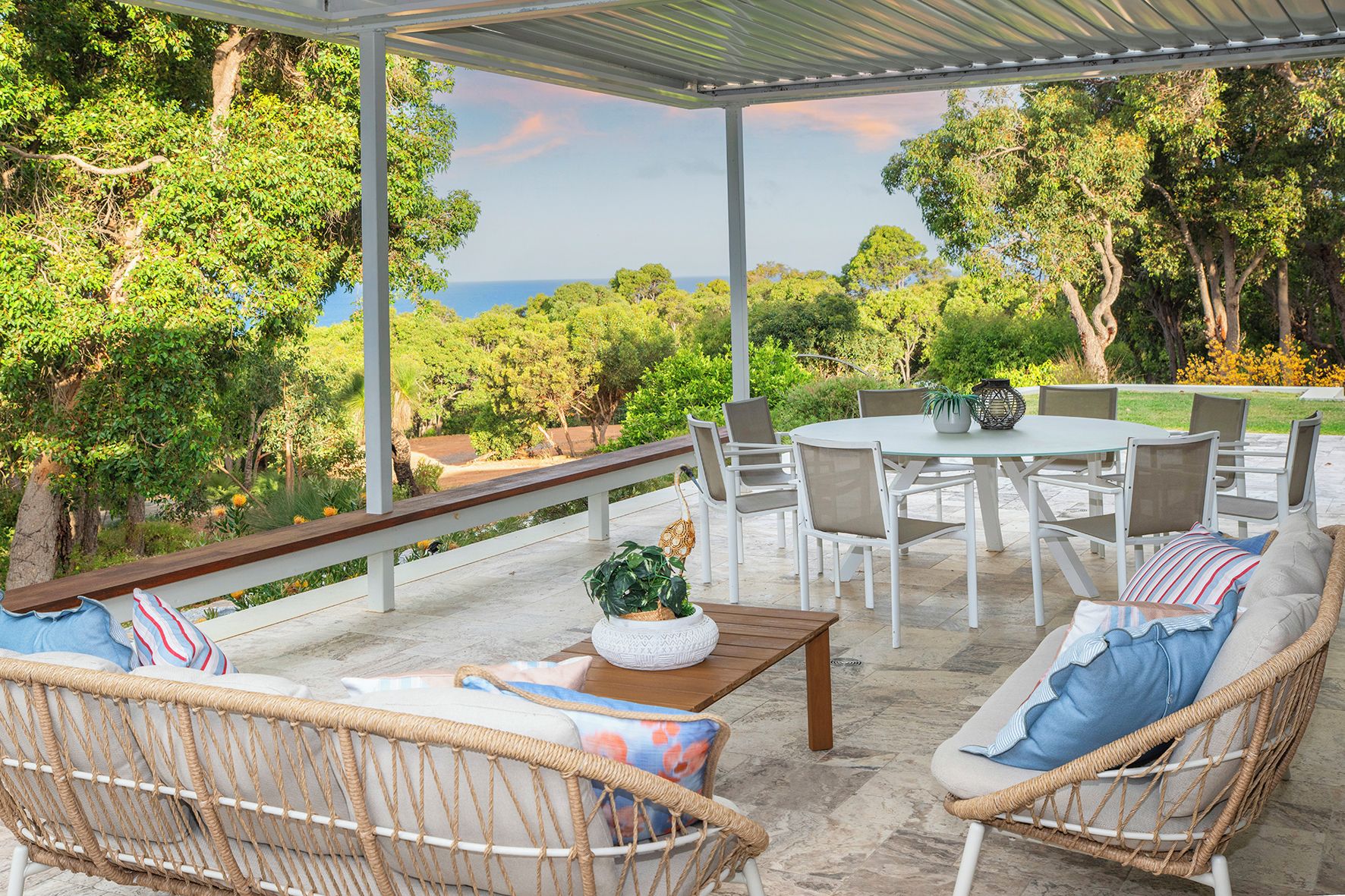 Une terrasse extérieure avec des meubles en osier, une table ronde et des chaises.