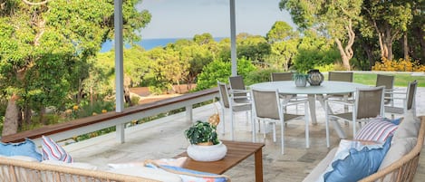 Une terrasse extérieure avec des meubles en osier, une table ronde et des chaises.