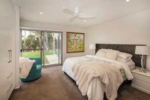A bedroom with a bed, a chair, a painting, a ceiling fan, and a view through a glass door. - Amira Vista - Views of Eagle Bay (Eagle Bay)
