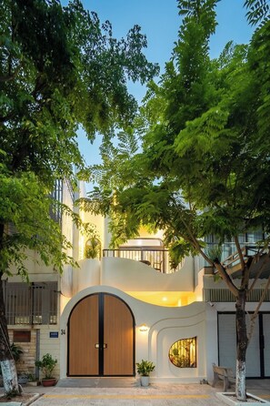 A modern building with a large arched entrance, a staircase, and a balcony with a railing. - Nimi Han River: 3BR-4 Beds | Private Pool & Beach (Đà Nẵng)