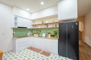 A compact kitchen with white cabinets, a black refrigerator, and a green backsplash. - Nimi Han River: 3BR-4 Beds | Private Pool & Beach (Đà Nẵng)