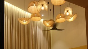 Una habitación de hotel con cama, cortinas, una lámpara de pared y una mesita de noche.