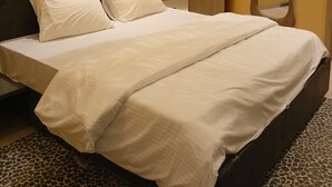 Una habitación de hotel con una cama, una mesita de noche, un espejo y un equipo de aire acondicionado en la pared.