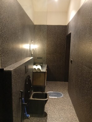 A compact bathroom with a toilet, bidet, and a towel dispenser. - Solaria Villa (Igatpuri)