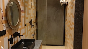 Un baño moderno con un lavamanos negro, un espejo y un perchero para toallas.