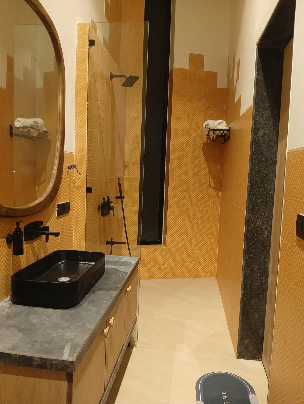A bathroom with a vanity, a mirror, a towel rack, and a shower area.