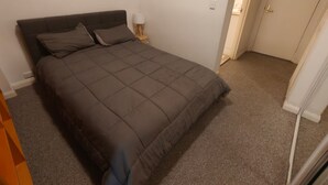 Un dormitorio con una cama, una mesita de noche y una lámpara.