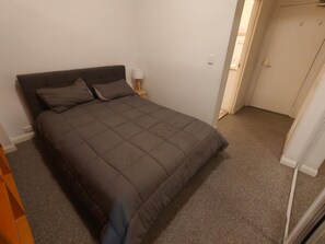 A bedroom with a bed, a bedside table, and a lamp. - Cozy Surry Hills Apt • Pool, Gym, Walk to All (Surry Hills)
