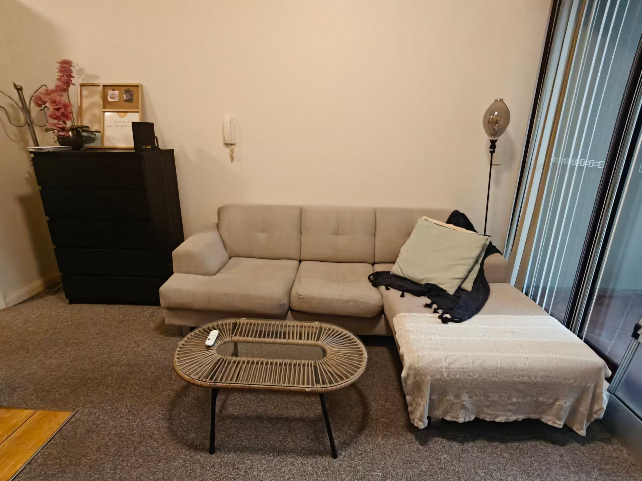 Una sala de estar con un sofá, una mesita, un jarrón decorativo y una lámpara.