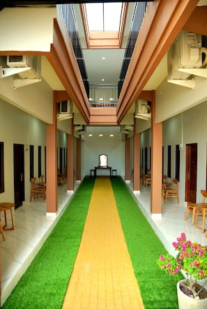 A hotel corridor with a central walkway, seating areas, and a ceiling with skylights.