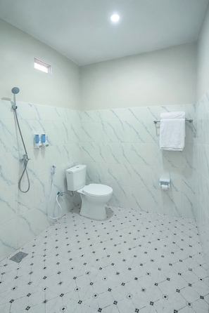 A bathroom with a toilet, shower, and tiled floor.