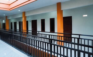 A corridor with a black railing, doors, and a ceiling with recessed lighting.