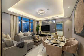 A modern living room with a sofa, coffee table, and dining area set for a meal. - Gogoto12 Luxury Skyline 2BR with Burj Khalifa view (Dubai)