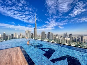 A rooftop infinity pool with a city skyline view, including a prominent skyscraper. - Gogoto12 Luxury Skyline 2BR with Burj Khalifa view (Dubai)