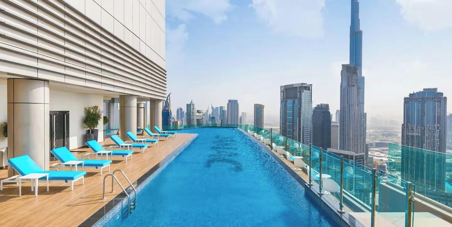 Pool på taget med liggestole og udsigt over byens skyline.