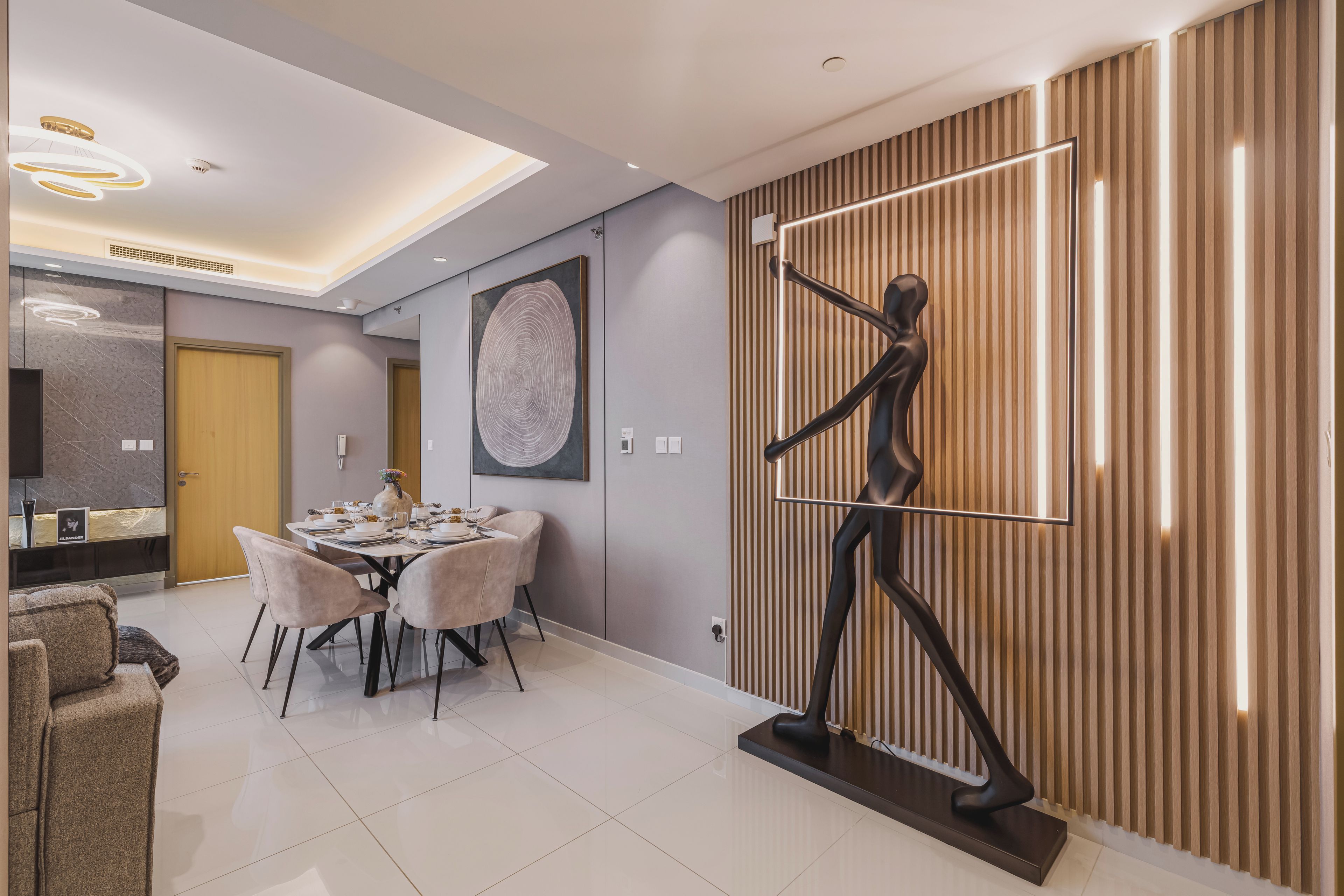 A modern dining area with a round table, chairs, and a decorative wall piece.