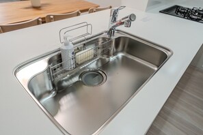 A modern kitchen with a stainless steel sink, a soap dispenser, and a dish rack. - Nikyo HARANAGI Villa Osaka (Osaka)