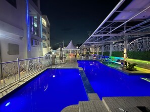 A swimming pool area with a covered seating area and a tent in the background. - SUMMIT GUEST HOUSE (Babenga)