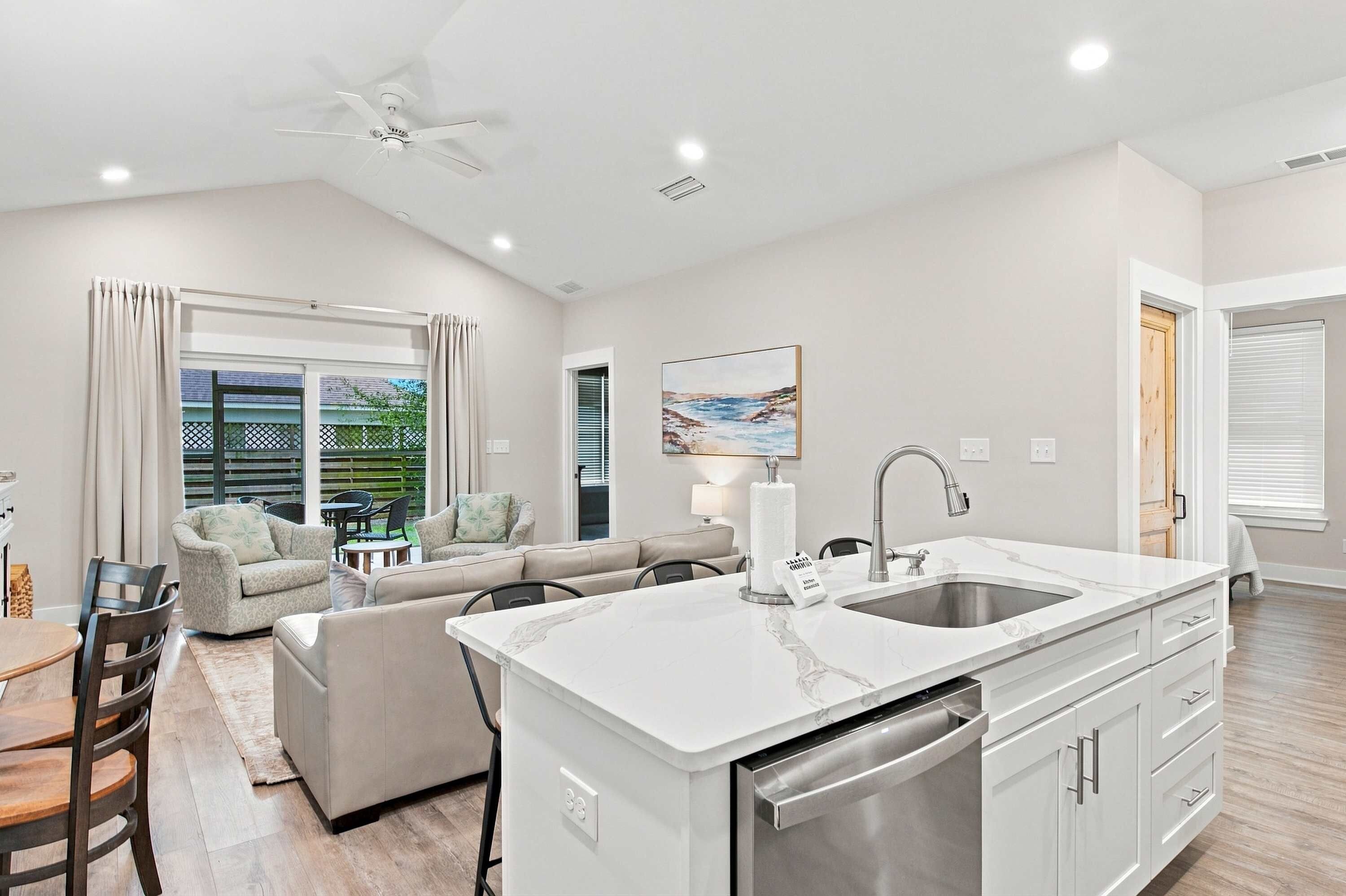 A modern kitchen with a large island, built-in dishwasher, and a dining area with a table and chairs.