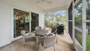 A covered patio with wicker furniture, a grill, and a view of the backyard. - Coastal Getaway in Perdido Key (Pensacola)