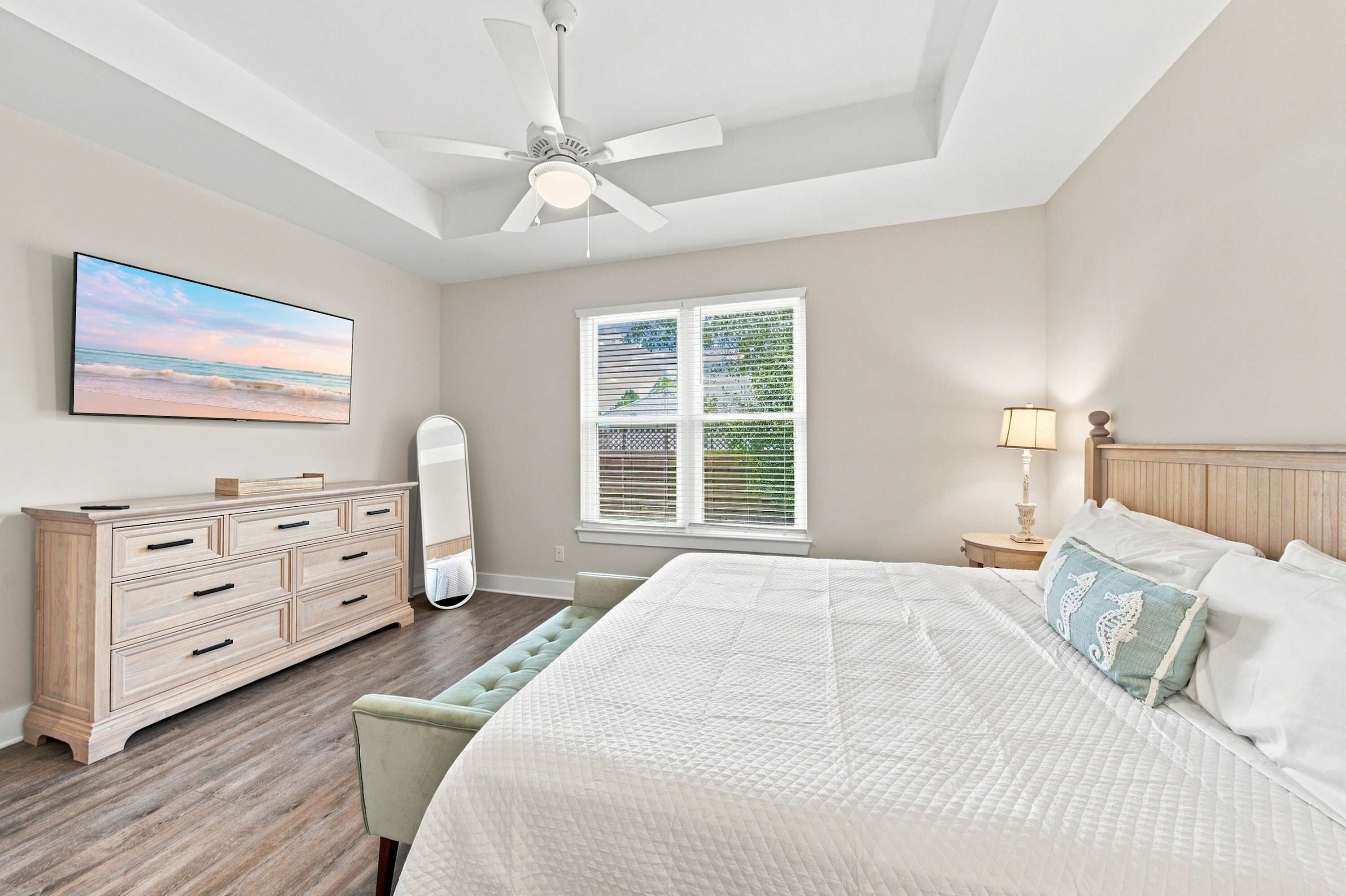 A bedroom with a bed, dresser, and a ceiling fan.