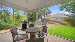 A covered patio with wicker furniture, a grill, and a view of a backyard. - Coastal Getaway in Perdido Key (Pensacola)