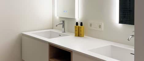 A modern bathroom with two sinks, a mirror, and built-in shelves.