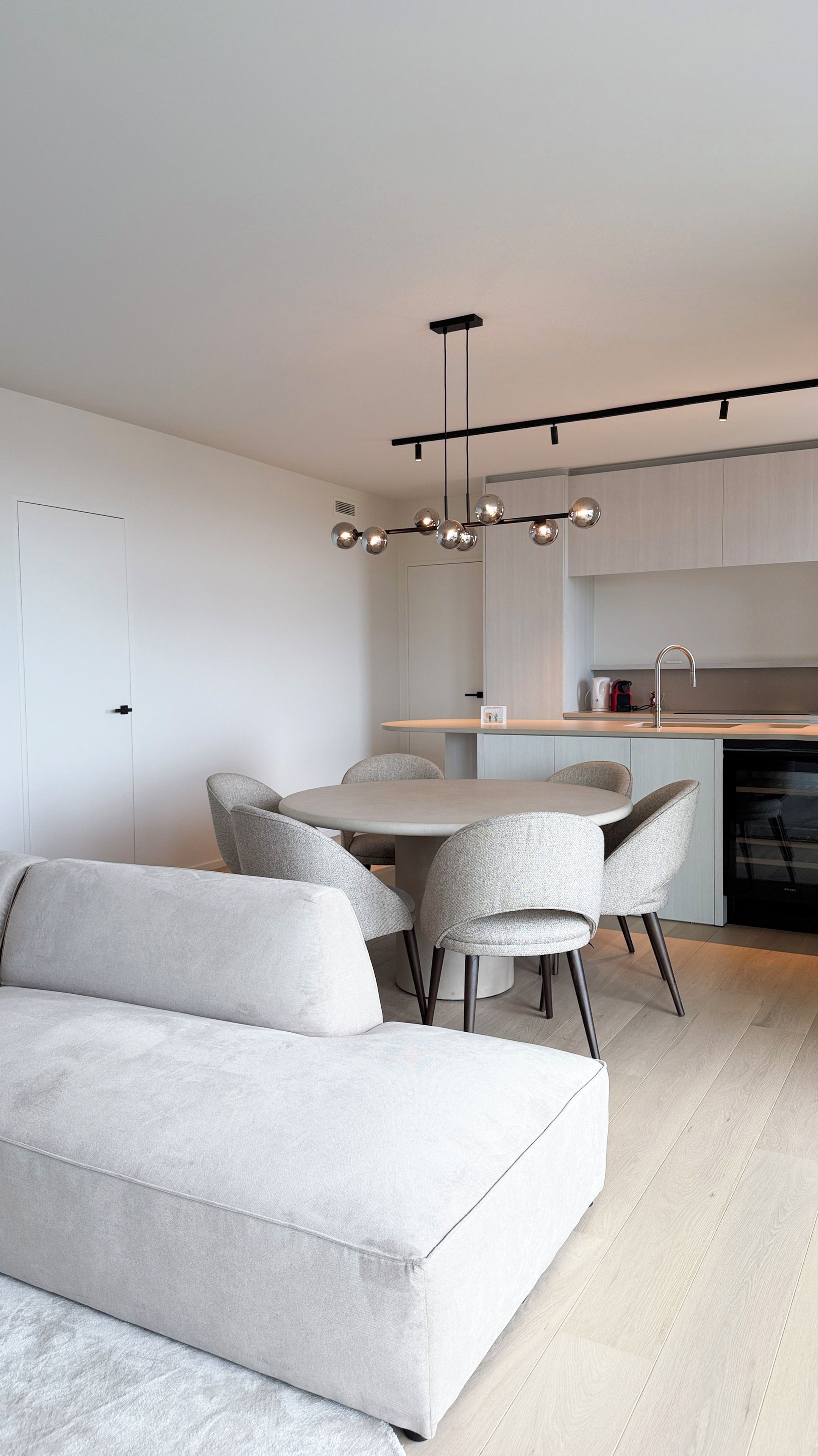 Une cuisine moderne avec un coin repas, comprenant un canapé, des chaises et une suspension.