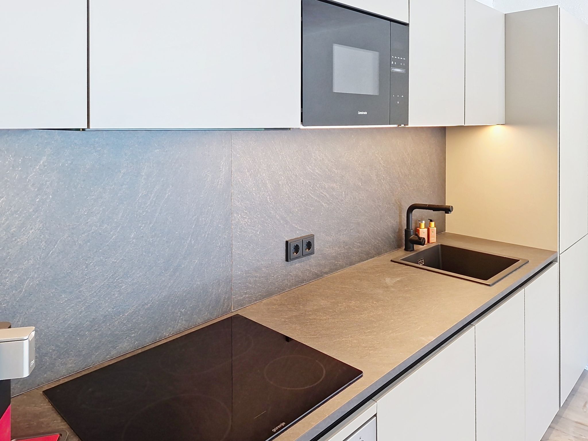 Una cocina moderna con microondas integrado, pileta doble y una amplia placa vitrocerámica.