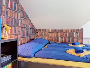 A bedroom with two beds, a bookshelf, and a desk with a lamp. - Ubytkostka by Interhome (Rokytnice nad Jizerou)