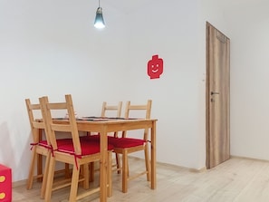 A dining area with a wooden table and chairs, a light fixture above, and a red wall decoration. - Ubytkostka by Interhome (Rokytnice nad Jizerou)