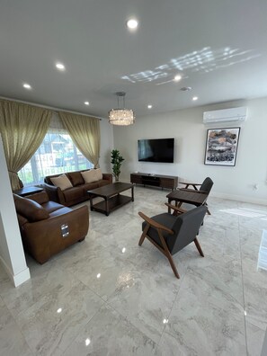 A modern living room with a sofa set, a coffee table, a TV, and a chandelier. - Beautiful modern home in a quiet neighbourhood in Charlottetown (Charlottetown)