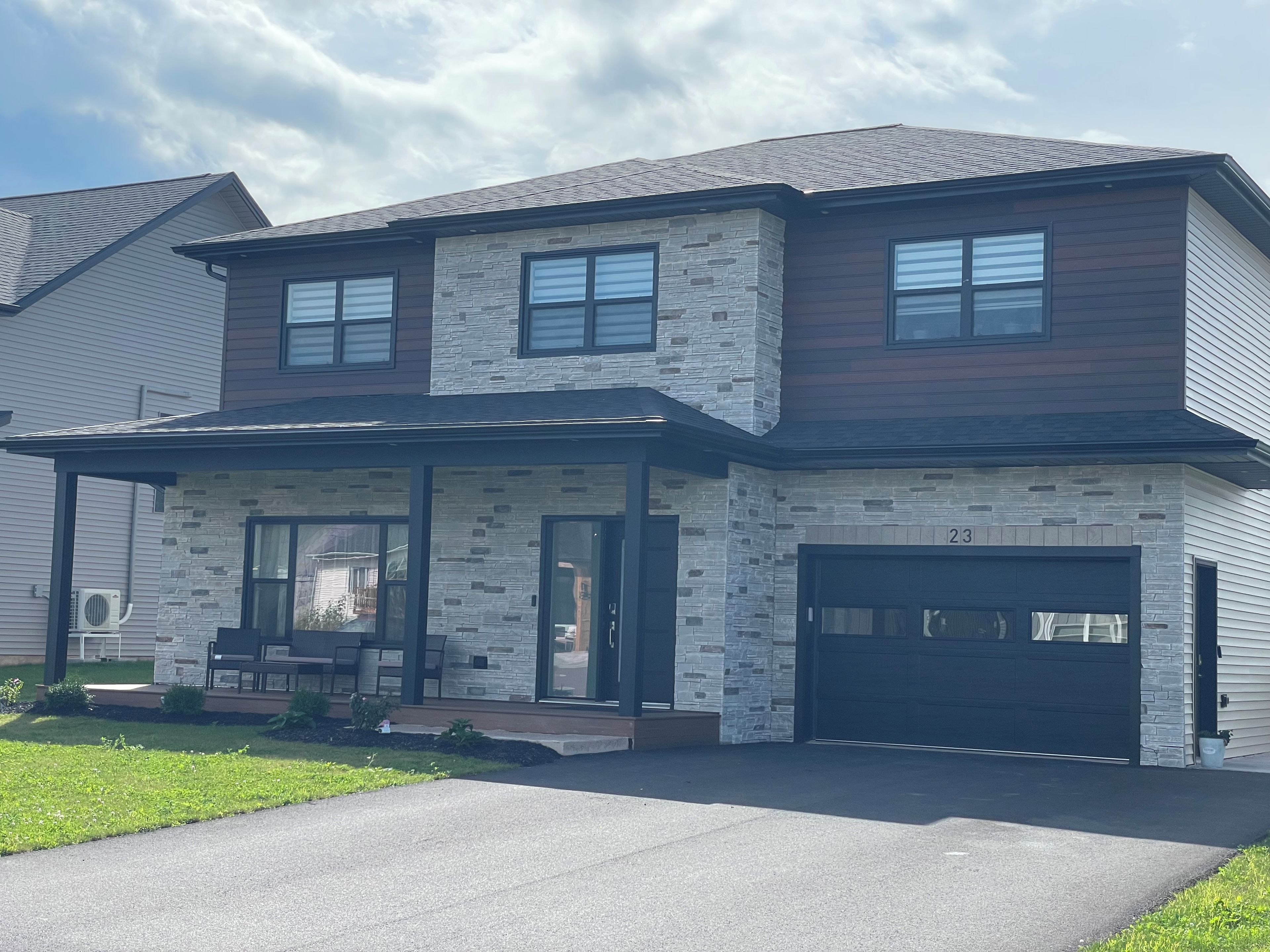 A two-story house with a stone facade, a front porch, and a garage.