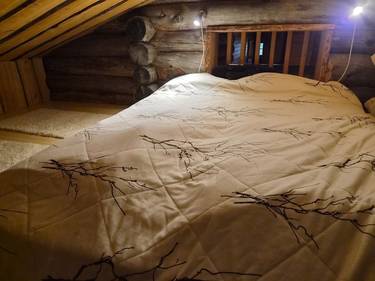 A bedroom with a bed, a wooden headboard, and a log wall.