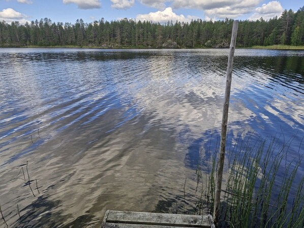 A calm lake with a wooden dock extending into the water, surrounded by dense forest. - Peaceful 5BR Lakeside Cabin | Sauna & Fireplace (Ruka)