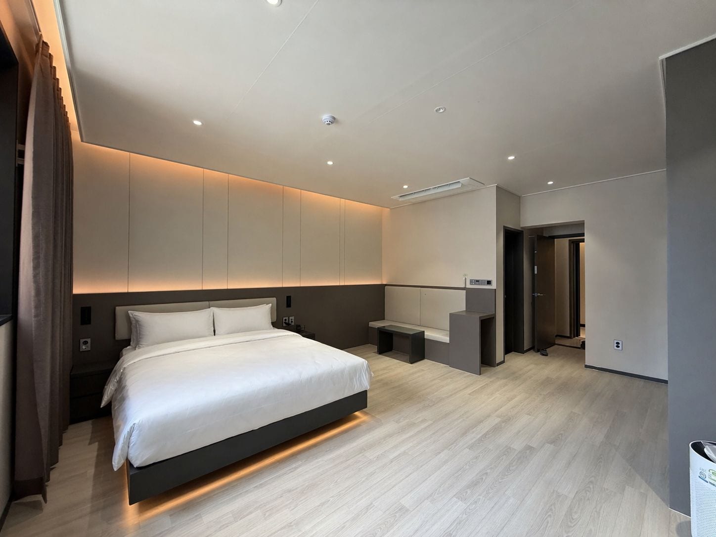 A modern hotel room with a large bed, a seating area, and a small desk.