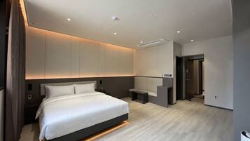 A modern hotel room with a large bed, a seating area, and a small desk.