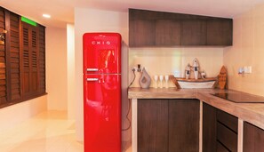 A kitchen with a red refrigerator, wooden cabinets, a countertop with decorative items, and a tiled floor.