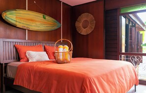 A bed with a basket of fruits, a round wall decoration, and a wooden ceiling.