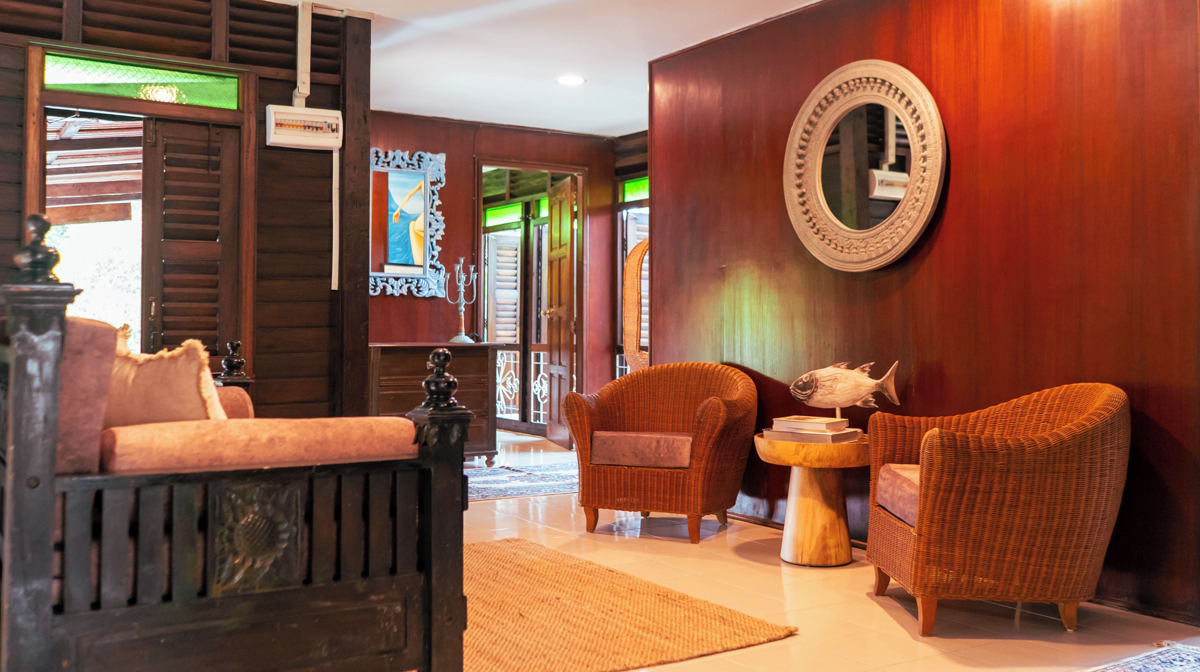 Una habitación tradicional con un sofá, dos sillones, una mesita con libros, un pez decorativo y un espejo en la pared.